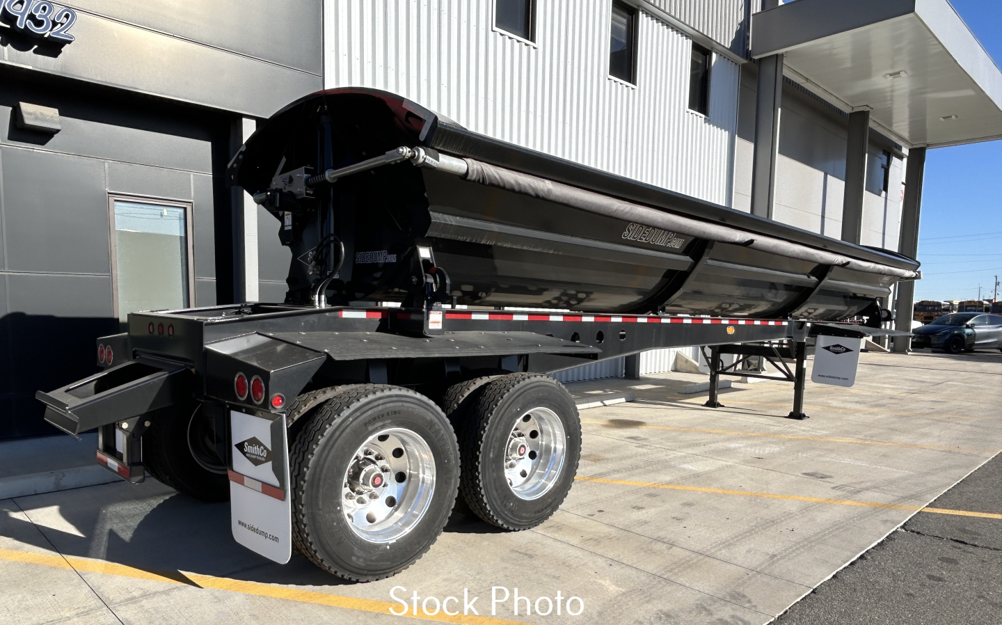 Dump trailer SX2-4034 side view showing dual rear tires and hydraulic dump mechanism with folded bed and supports.