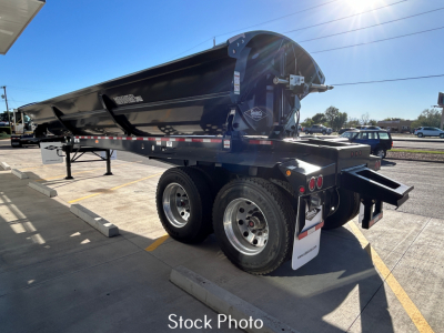 Dump trailer showing dual rear wheels and black SX2-4034 Smithco dump trailer with a raised bed, rear underride attachment, and reflective tape.