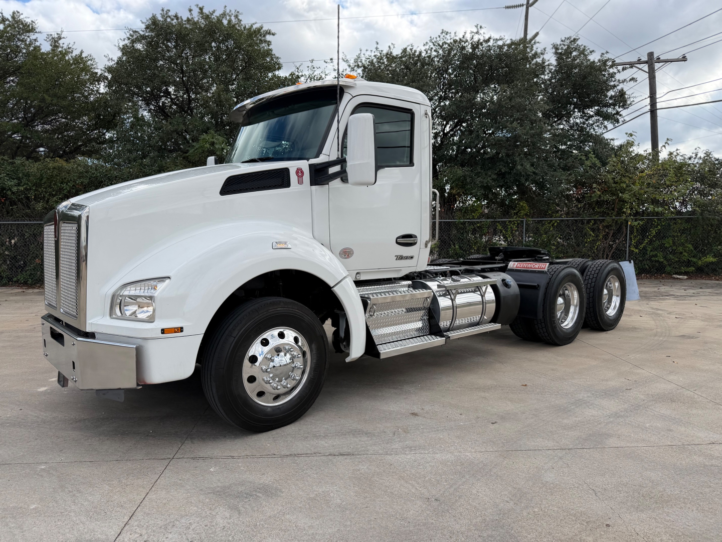 Kenworth T880 truck in white, front-left view, showing cab, chrome bumper, dual rear axles, and fuel tanks.