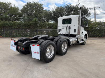 Kenworth T880 conventional daycab tractor rear three-quarter view showing dual rear axles and fuel tanks.