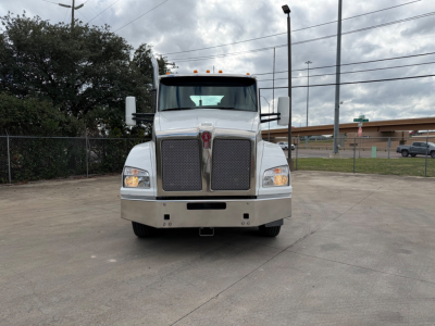 Kenworth T880 conventional daycab front view showing large grille, bumper, and headlights in a parking lot.