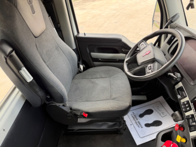 Kenworth T880 interior driver seat and steering wheel view showing grey fabric seats and dashboard. 