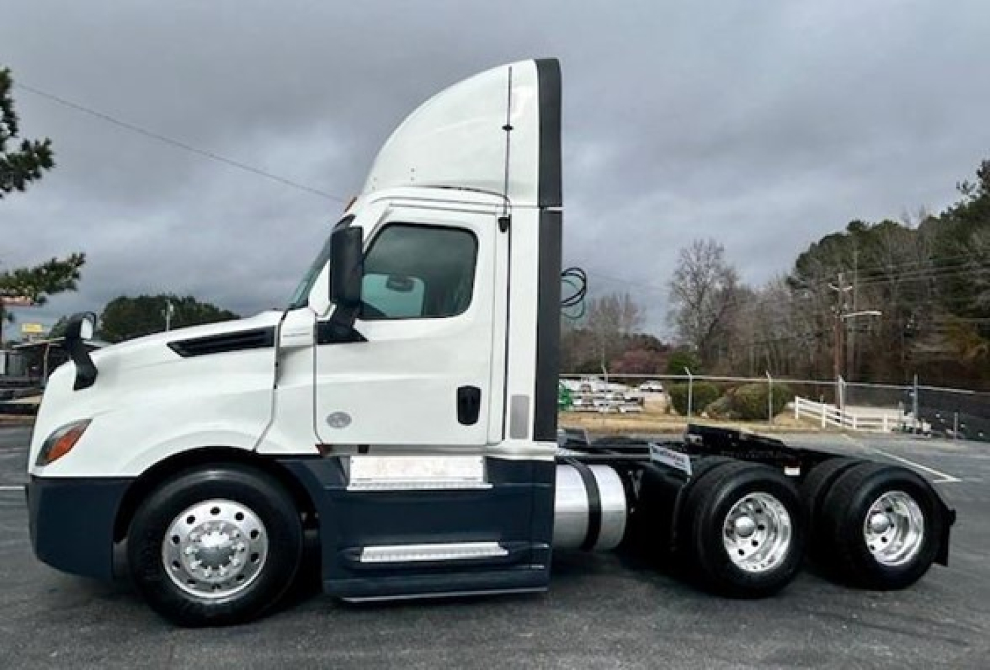 Freightliner Cascadia 126 day cab tractor in white with sleeper height, side view showing cab and rear axles.