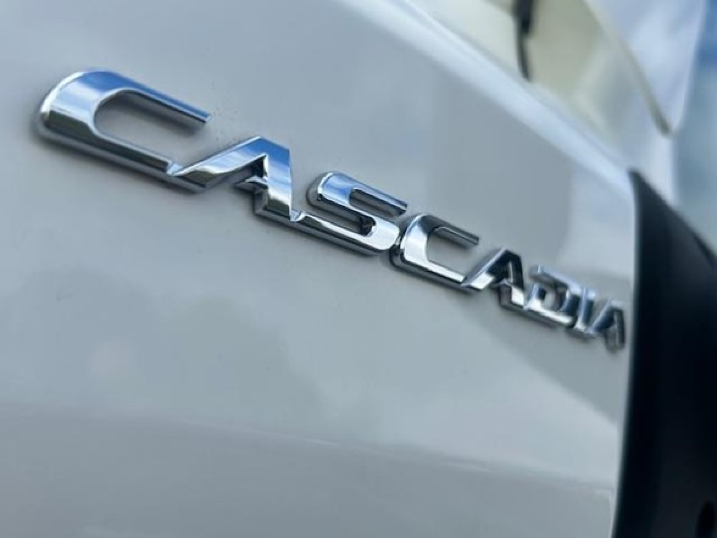 Casadia badge on a Freightliner Cascadia side showing 'CASCADIA' chrome lettering on a light gray surface.