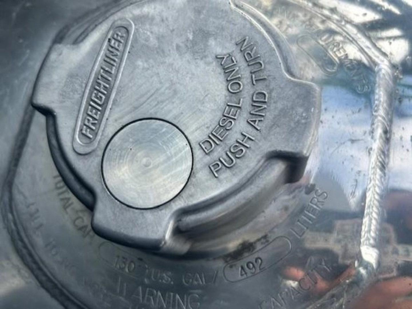 Freightliner diesel fuel cap showing 'FREIGHTLINER' and 'DIESEL ONLY PUSH AND TURN' along with capacity markings.