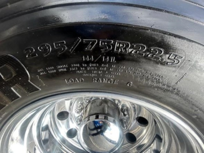 Heavy truck tire with alphanumeric markings: 295/75R22.5 and load range G; chrome wheel center cap details visible.
