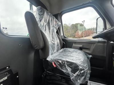 Truck cab interior with plastic seat coverings, driver seat and passenger side visible, window view outside.