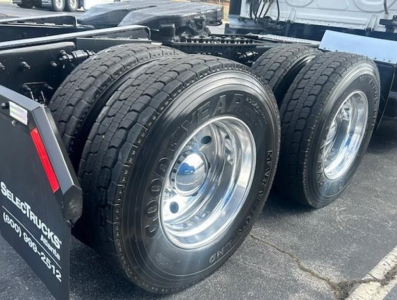 Freightliner Cascadia 126 rear wheel area showing dual rear tires and chrome rims; Goodyear tires with tread visible; part of truck chassis and mudflap visible.
