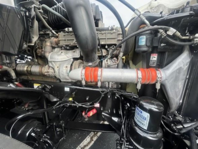 Freightliner Cascadia engine bay showing turbocharger, intercooler piping, hoses, and black cylindrical filter canister.