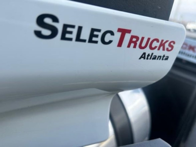 Vehicle exterior showing a white Freightliner Cascadia with SelectTrucks Atlanta branding on the tail area.