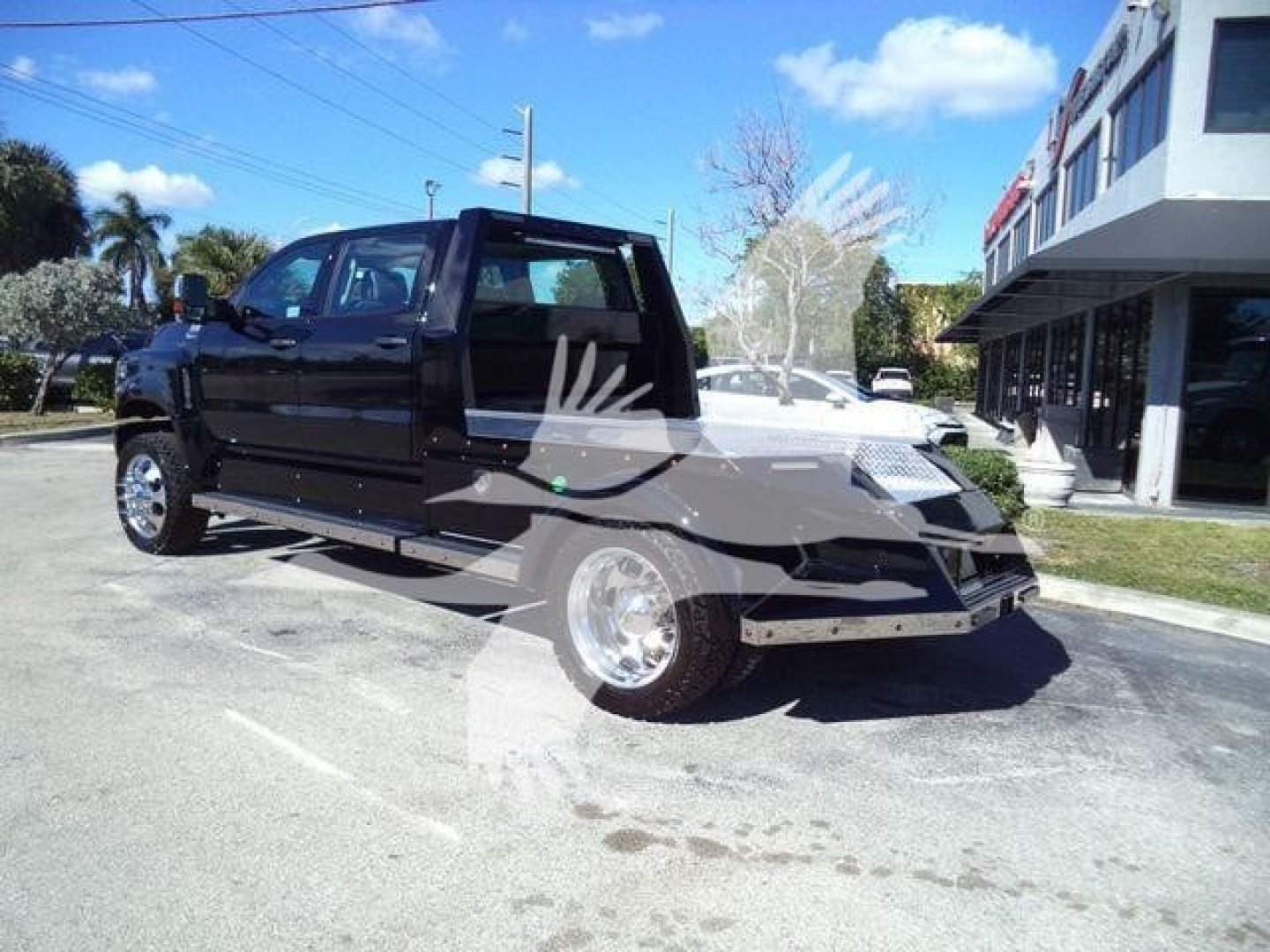 Truck in showroom lot showing 2023 International CV, black cab with open cargo bed and chrome wheels.