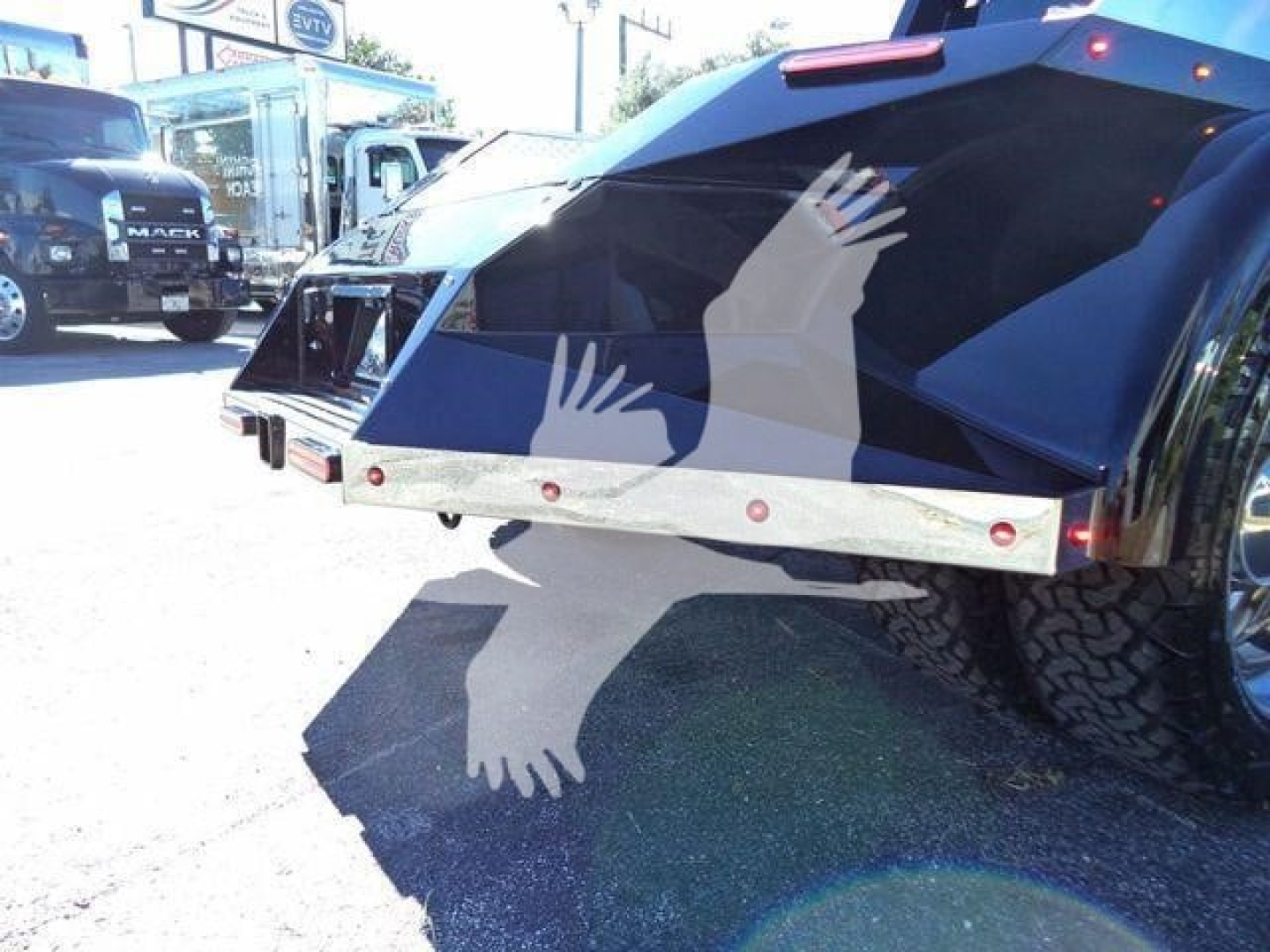 Truck bed area showing rear of a 2023 International CV with chrome bumper and black tailgate, visible safety lights and wheel.