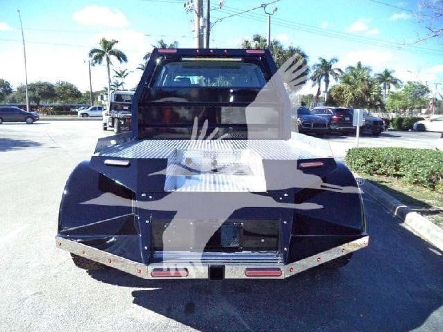 Truck bed of a new 2023 International CV tow truck, rear view with aluminum diamond-plate bed and mirrored tail lights.