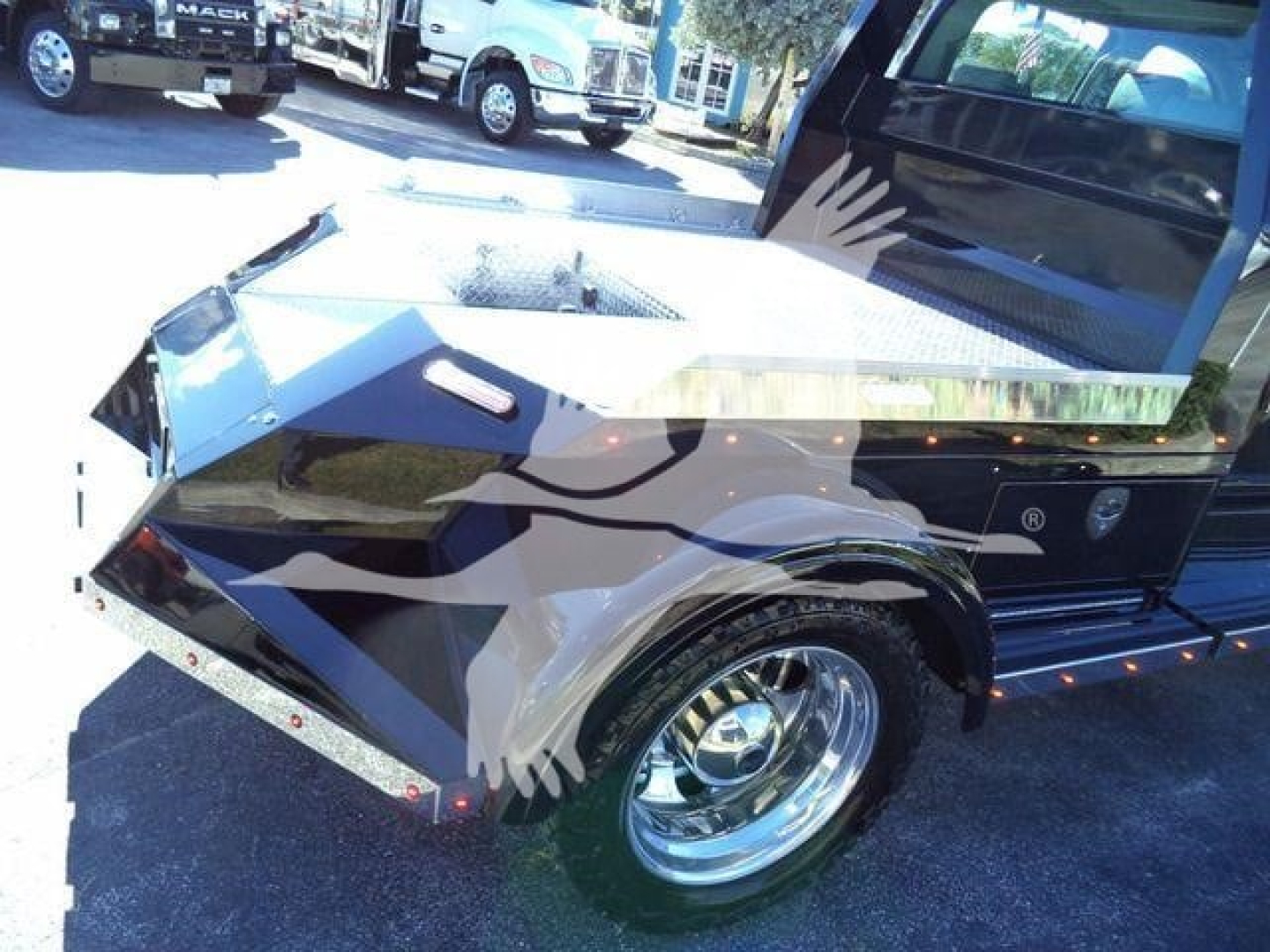 Trucks in a dealership lot showing a 2023 International CV Toter truck with a custom angular front fender and chrome wheel, stock number STEPSIDEHAULER1FM