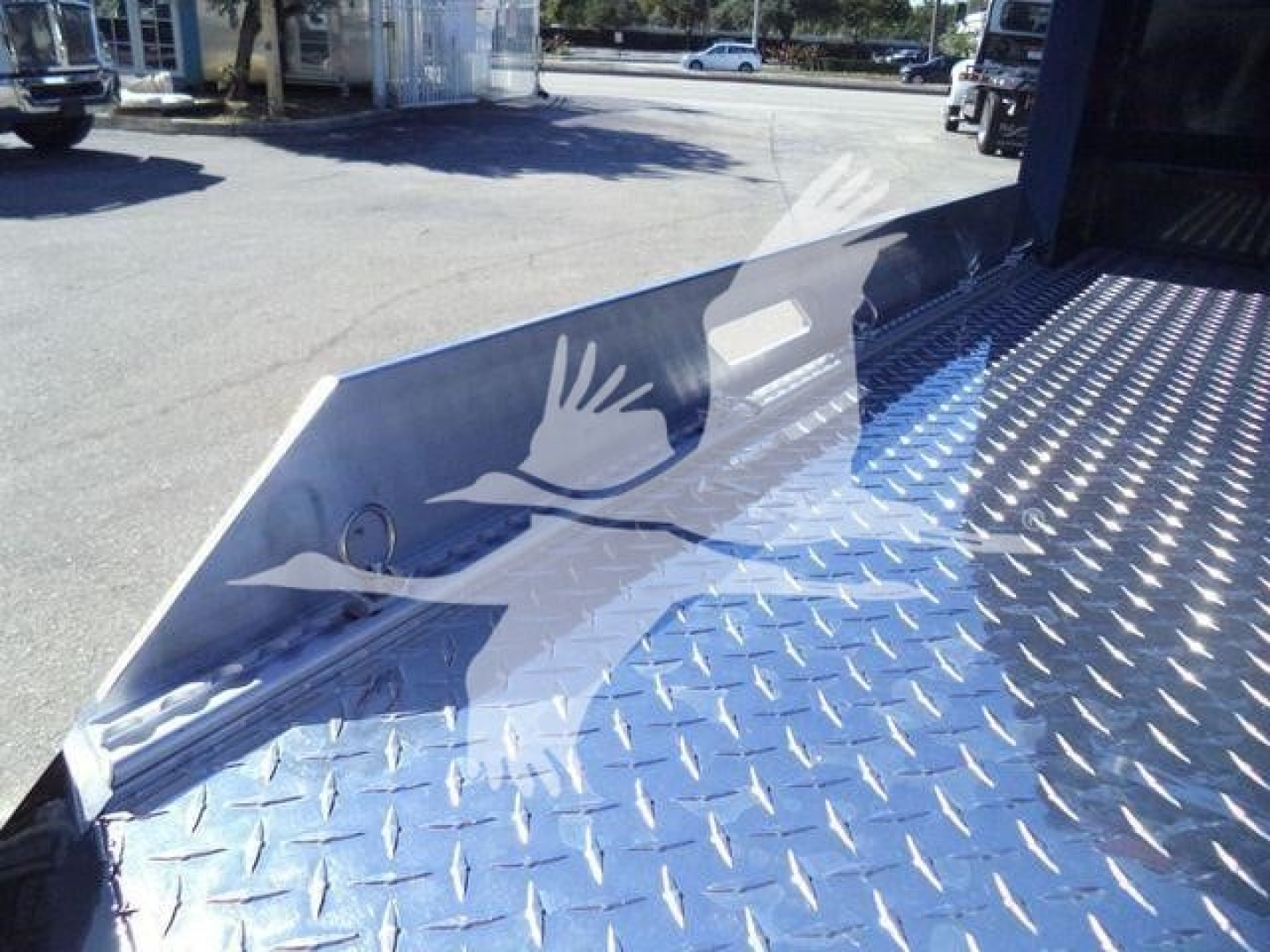 Truck bed with diamond plate aluminum and angled side ramp; no visible text.
