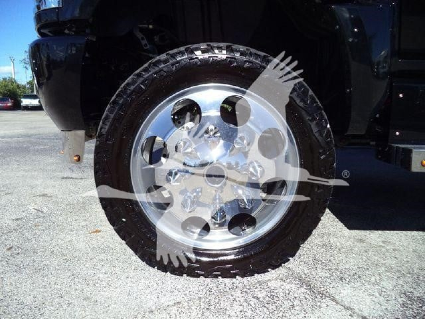 Wheel well and chrome alloy wheel of a truck with tire tread visible.