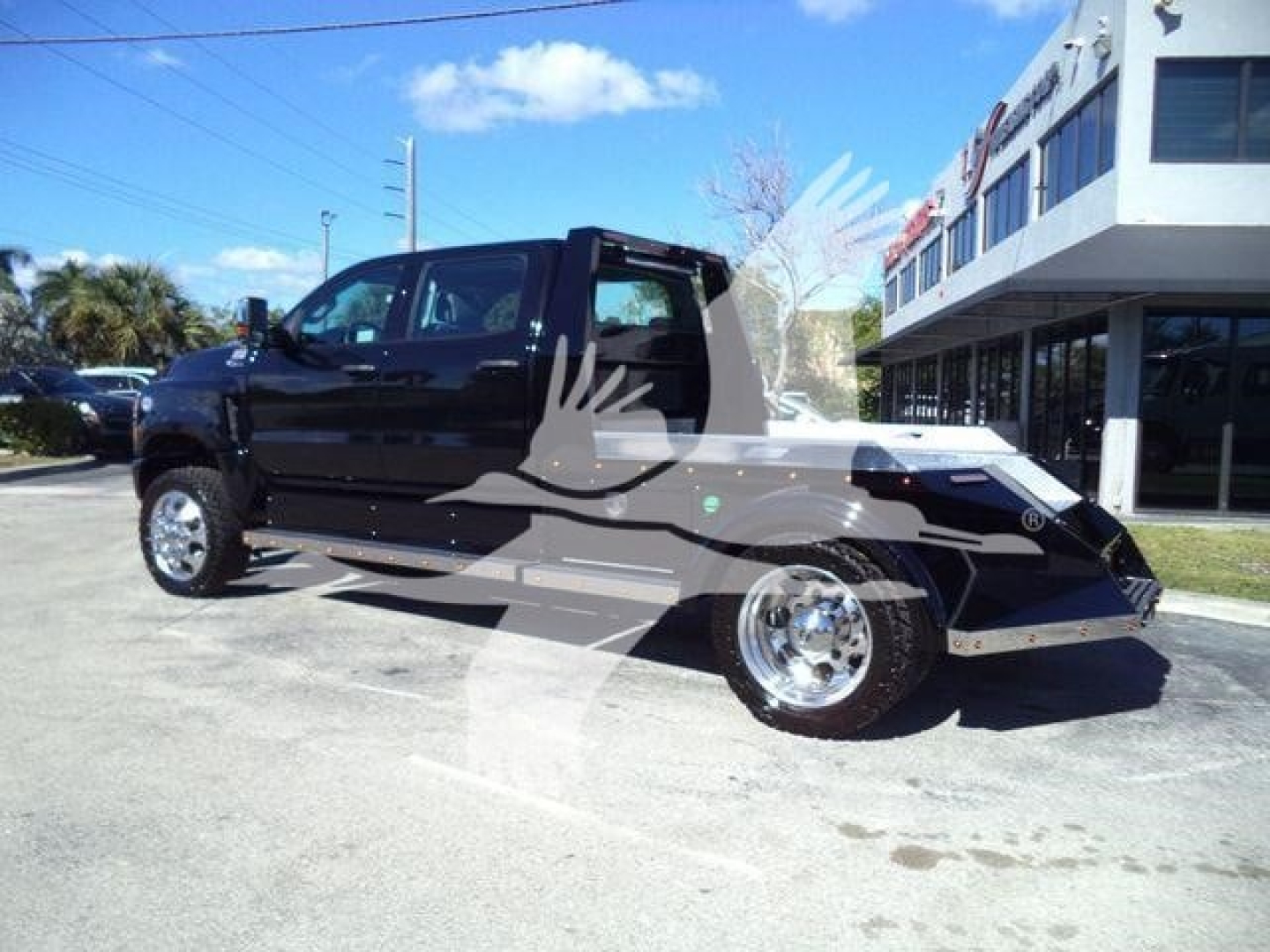 Truck in a dealership lot showing a black 2023 International CV with flashy chrome wheels, open cab, and a creampower aluminum front bumper. Watermark logo across.