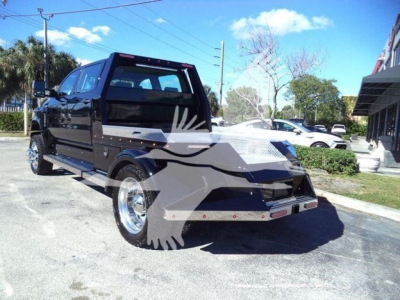 Truck cab and flatbed body of a 2023 International CV truck in a parking lot, side view with black finish and chrome wheels.