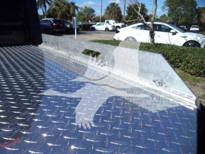 Truck bed with diamond plate surface and side low walls, view from rear showing metal surface and tie-down points.