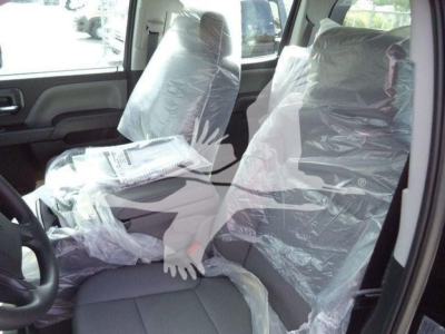 Interior of a new 2023 International CV pickup truck showing front seats wrapped in protective plastic and light gray upholstery.