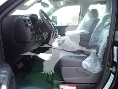 Interior view of a new 2023 International CV truck cab showing front seats wrapped in plastic and steering wheel visible.