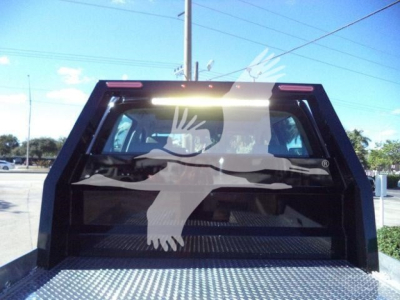 Rear view of a black truck bed showing a large white silhouette graphic on the back window. The truck bed has diamond plate flooring and a small tailgate opening.