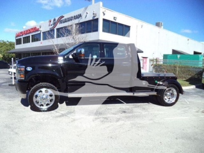 Truck in front of building showing a black and gray International CV utility hauler with large flames graphic on door and extended cab.