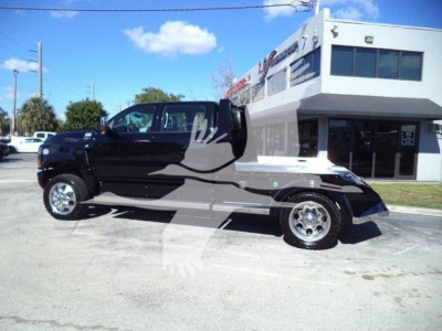 Truck cab in front view with black cab and flatbed, International CV model, dealership building in background, stock number STEPSIDEHAULER1FM.