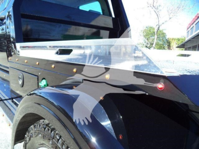 Truck cab with aluminum headache rack and clear wind deflector; front fender and wheel well visible.