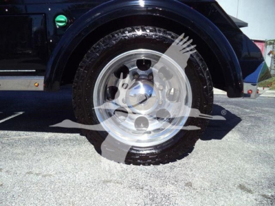 Truck wheel and fender showing polished alloy wheel and tire tread.