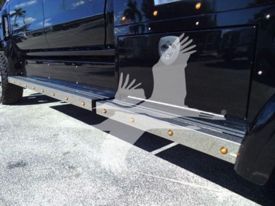 Truck side view showing running board and black cab with stock number STEPSIDEHAULER1FM, step bars with orange reflectors along the lower body.