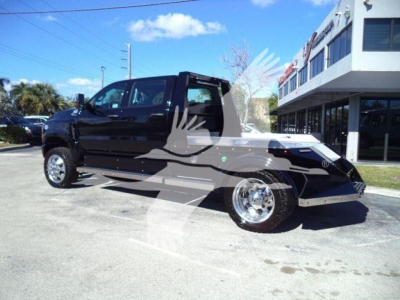 Truck in a dealership lot showing a black 2023 International CV with flashy chrome wheels, open cab, and a creampower aluminum front bumper. Watermark logo across.