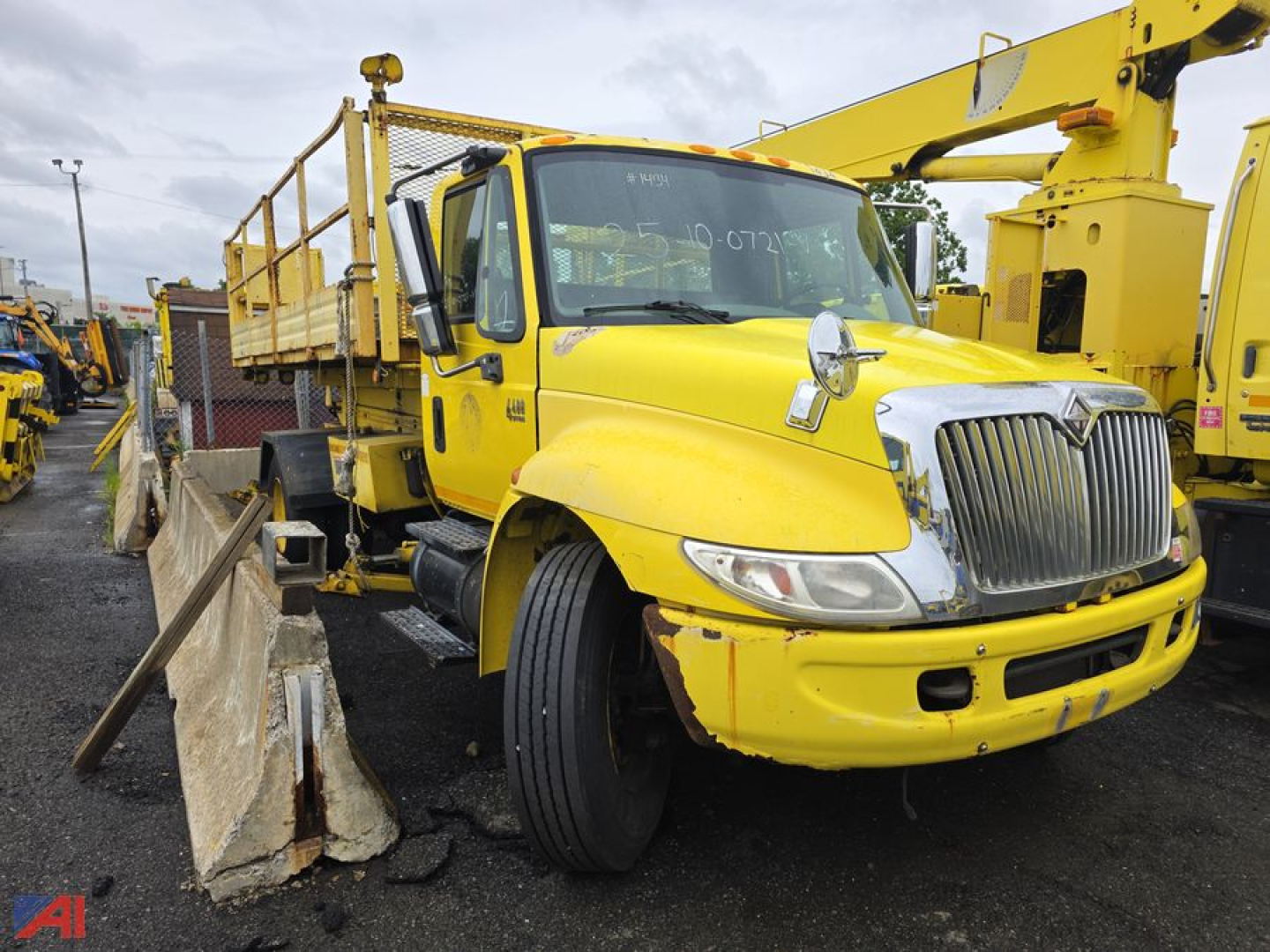 Truck side view of a yellow 2004 International DuraStar 4400 stake bed with Altec aerial crane, front grille, and large tires.
