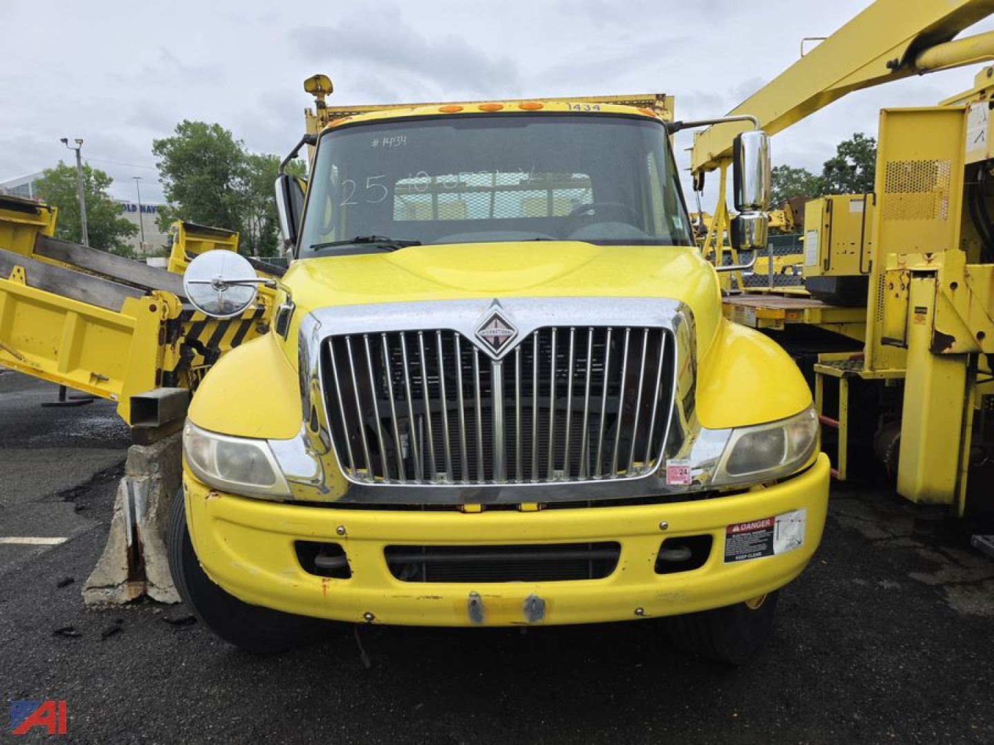 Front view of a yellow International DuraStar 4400 3.5-ton stake bed truck with Altec aerial equipment, chrome grille, and rounded headlights.