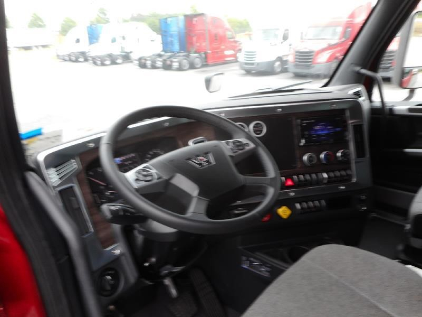 Cab interior of a new 2027 Western Star 47X truck showing steering wheel, digital dashboard, center touchscreen, and controls.