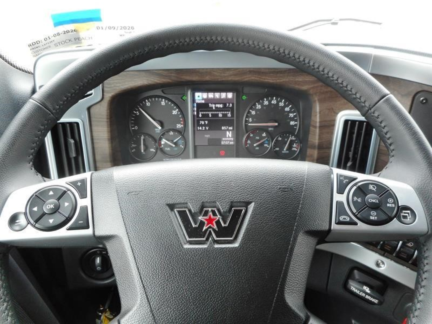 Truck cabin view of a Western Star instrument cluster and steering wheel with woodgrain dash trim showing various gauges.