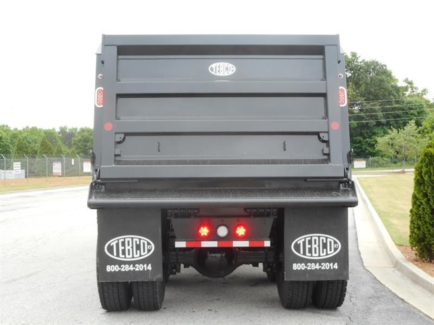 Western Star 47X dump truck rear view showing dual rear wheels and tailgate with TEBCD logos and contact numbers.