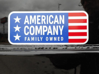 Sticker on vehicle window reading AMERICAN COMPANY FAMILY OWNED with white stars on blue background and red-and-white stripes to the right.