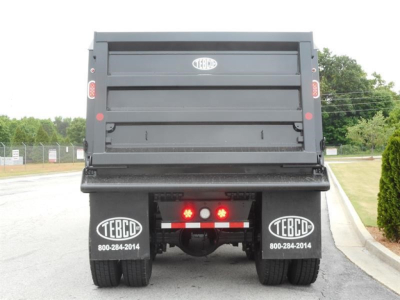 Western Star 47X dump truck rear view showing dual rear wheels and tailgate with TEBCD logos and contact numbers.