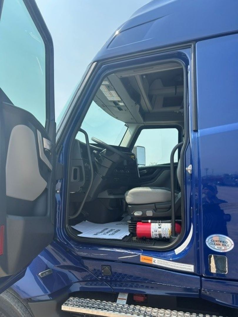 Volvo VNL truck cab interior viewed from open door showing steering wheel, seat, and dashboard area.