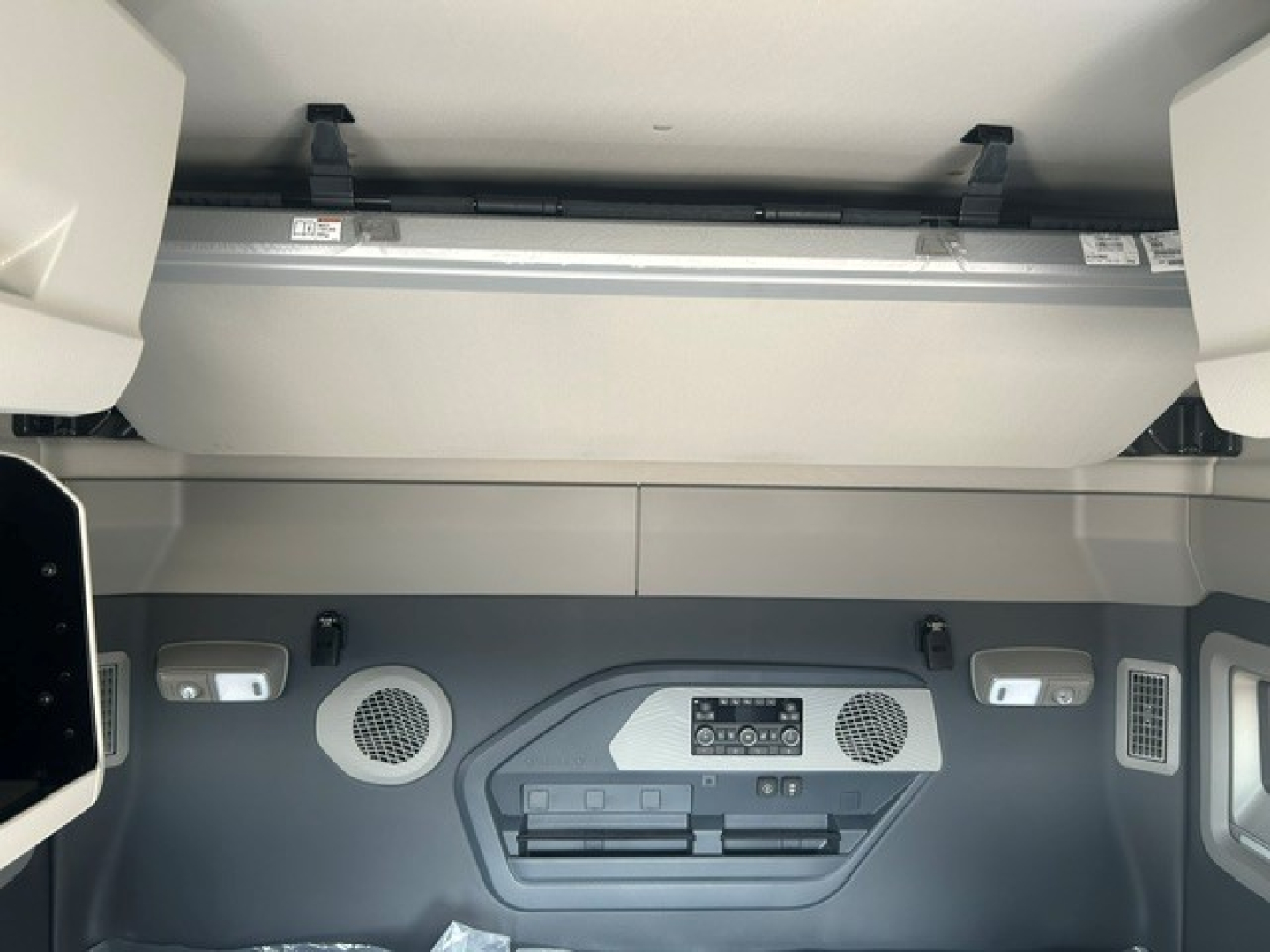 Volvo VNL cabin area showing overhead storage and control panel with speakers and vents in the dash view