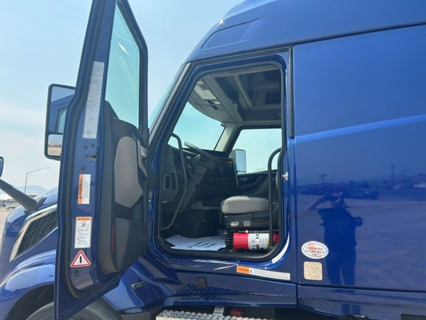 Blue Volvo VNL64T840 cab interior and open door showing driver seat and dashboard.