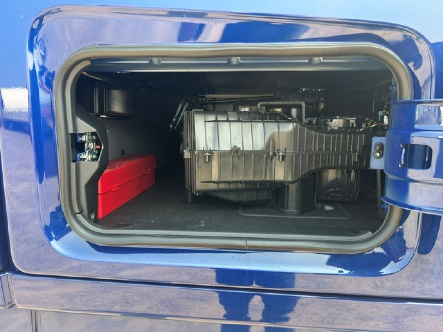 Volvo VNL truck side storage compartment showing auxiliary battery and insulated fuel tank in the forward bay.