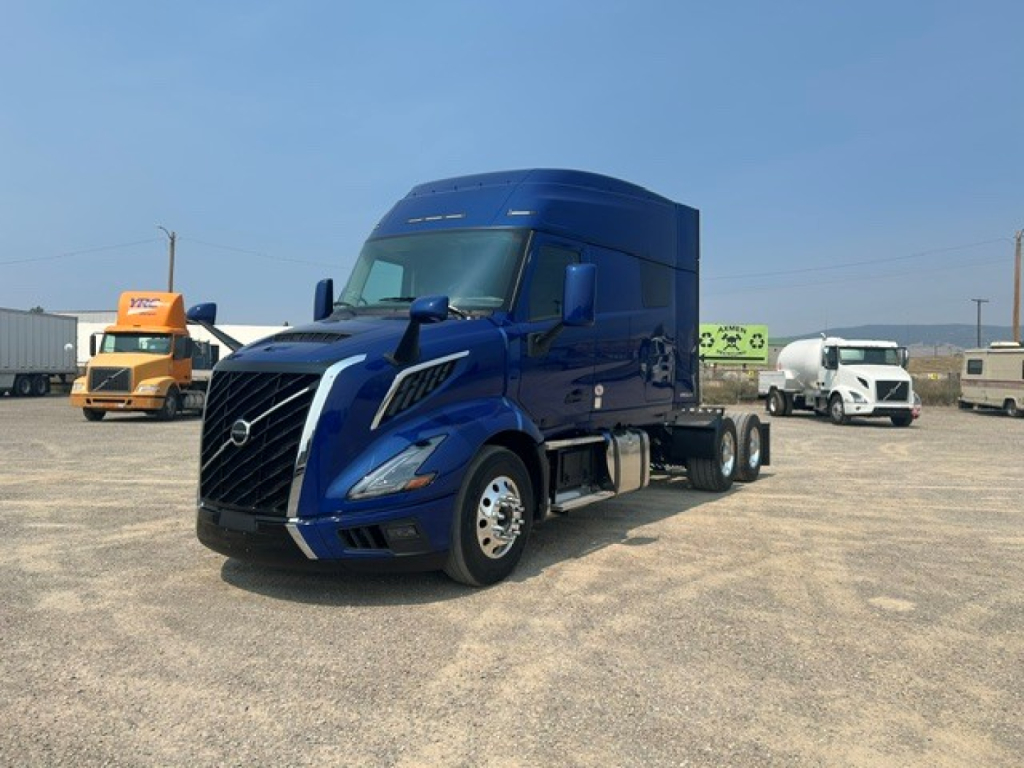 Blue Volvo VNL64T840 semi-truck in a parking lot, front-left view.