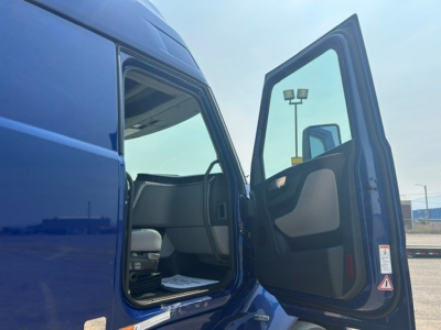 Volvo VNL truck cab door open showing blue exterior and interior seating with door panel and window.