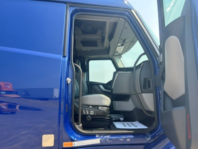 Cab interior of a blue Volvo VNL64T840 truck cab showing driver seat and dashboard from the doorway.