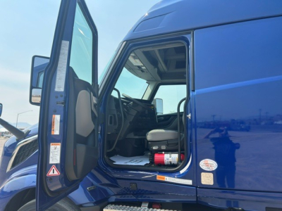 Blue Volvo VNL64T840 cab interior and open door showing driver seat and dashboard.