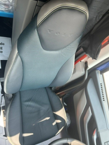 Seat backrest with Volvo logo on the headrest visible in cab interior of a 2027 Volvo VNL64T840 truck.