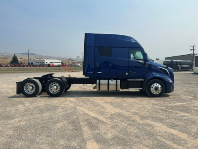 Volvo VNL64T840 semi tractor in blue side view showing sleeper cab and rear axles.