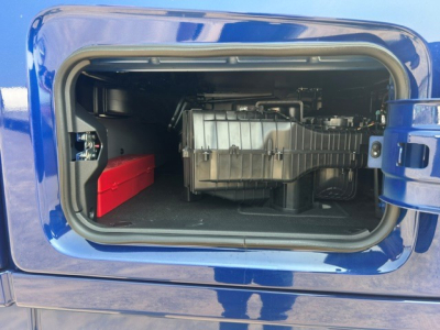 Volvo VNL truck side storage compartment showing auxiliary battery and insulated fuel tank in the forward bay.